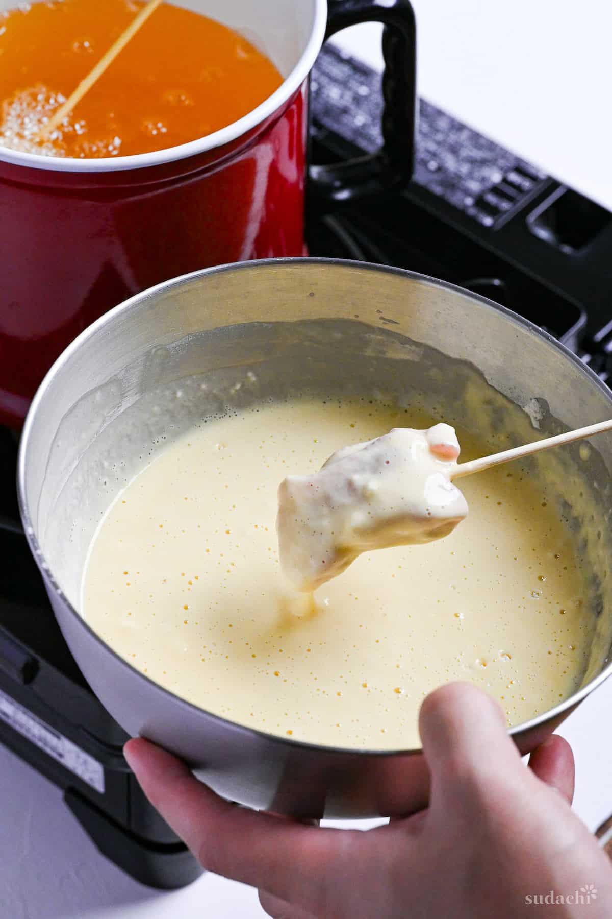 coating pork on a skewer with egg batter ready for panko coating