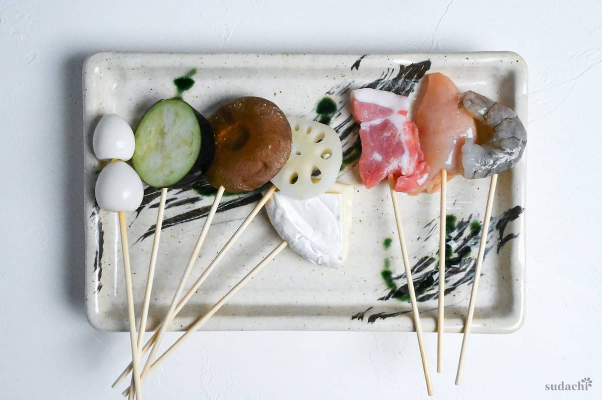 raw ingredients on bamboo skewers on a plate ready for battering to make kushi age