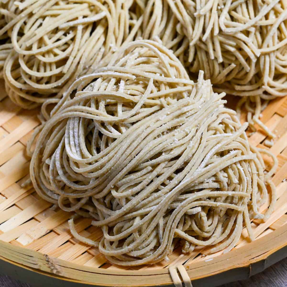 three bundles of homemade soba noodles on a bamboo tray