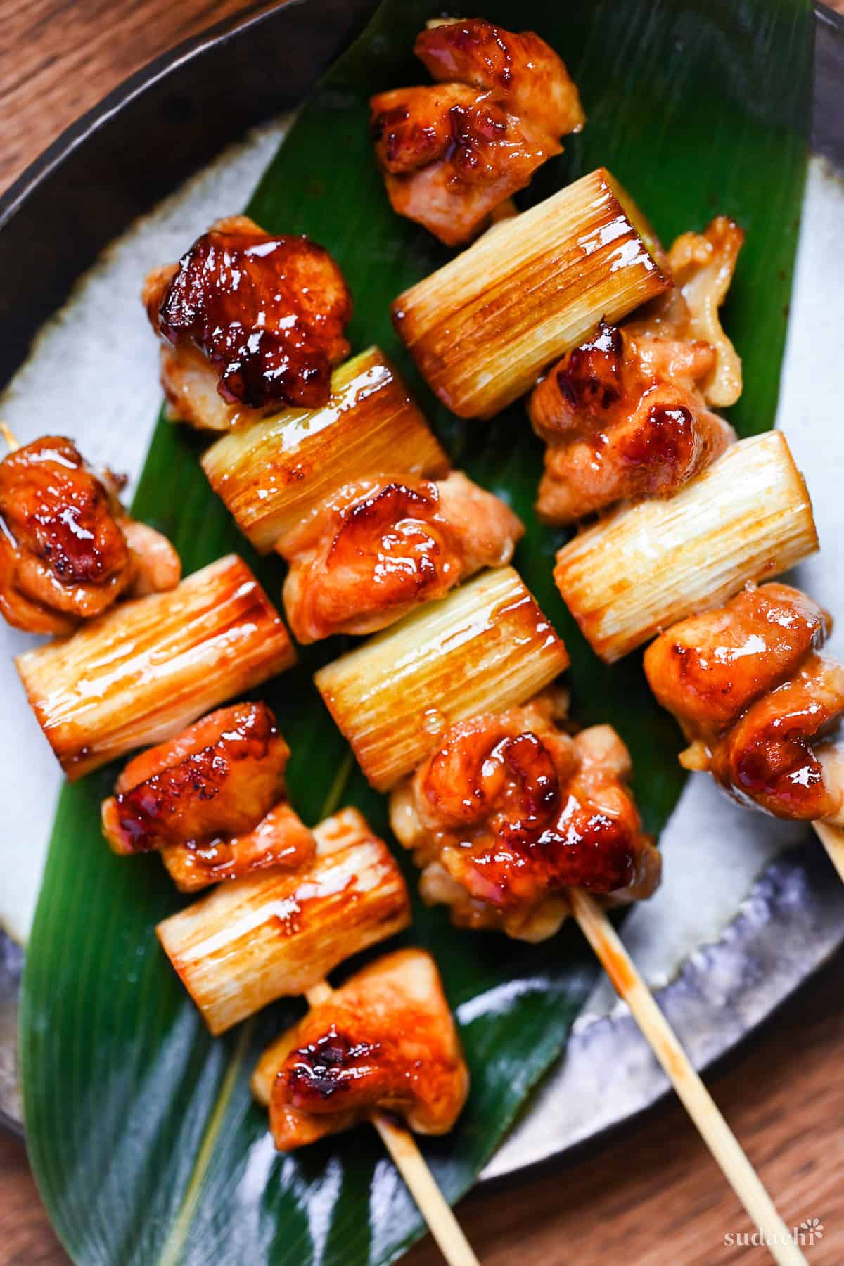 Three yakitori on a plate made with chicken thigh and Japanese leeks on a skewer coated in homemade sauce