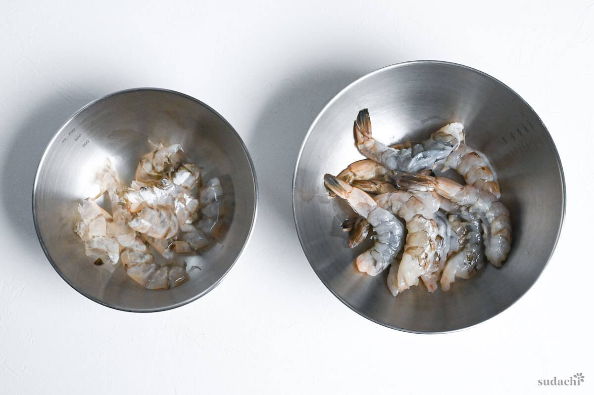 Shrimp separated from shells and placed in separate bowls on a white background