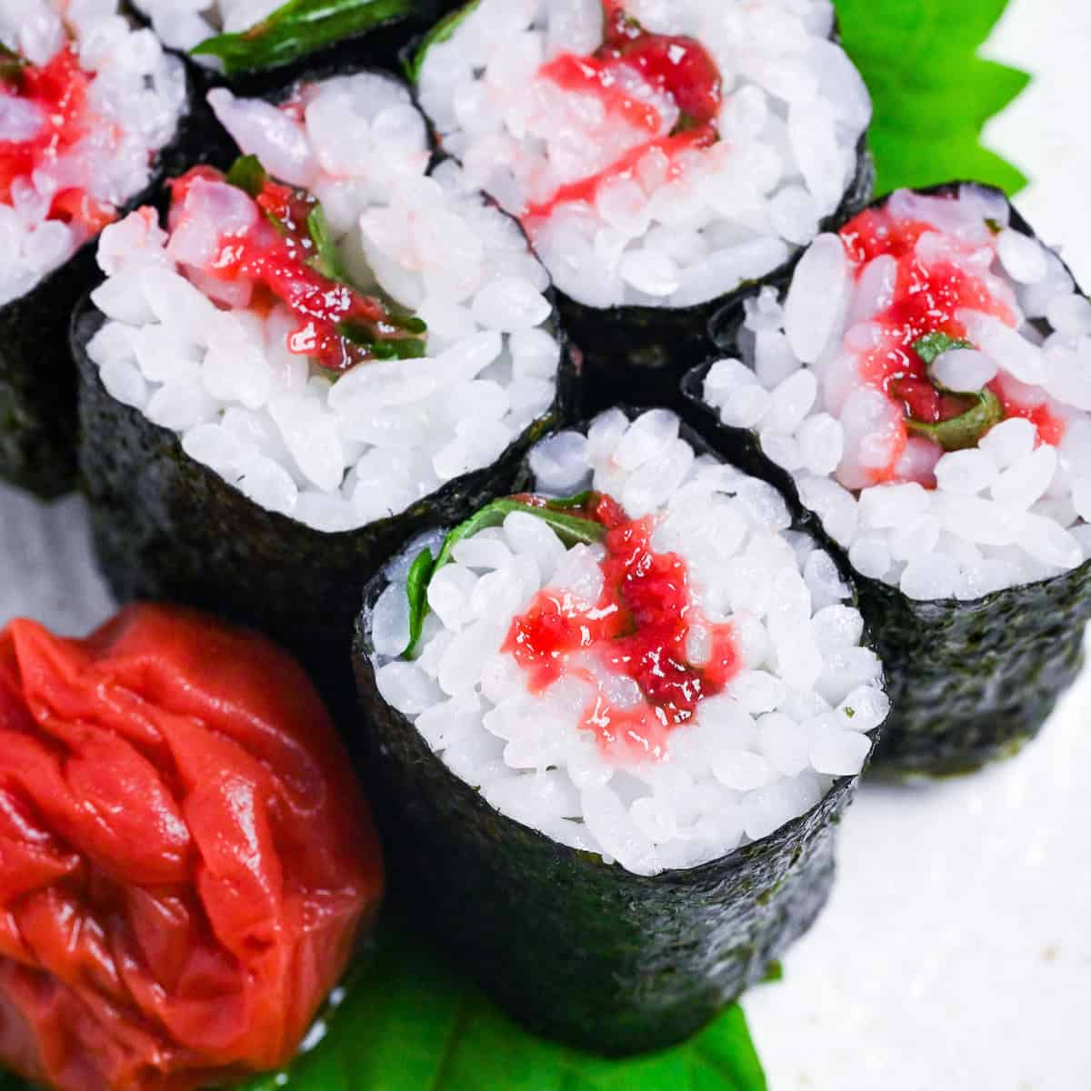 6 sushi rolls filled with umeboshi pickled plums and perilla leaves on a cream colored plate