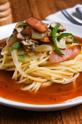 ankake spaghetti on a white plate with salt and pepper shakers in the background