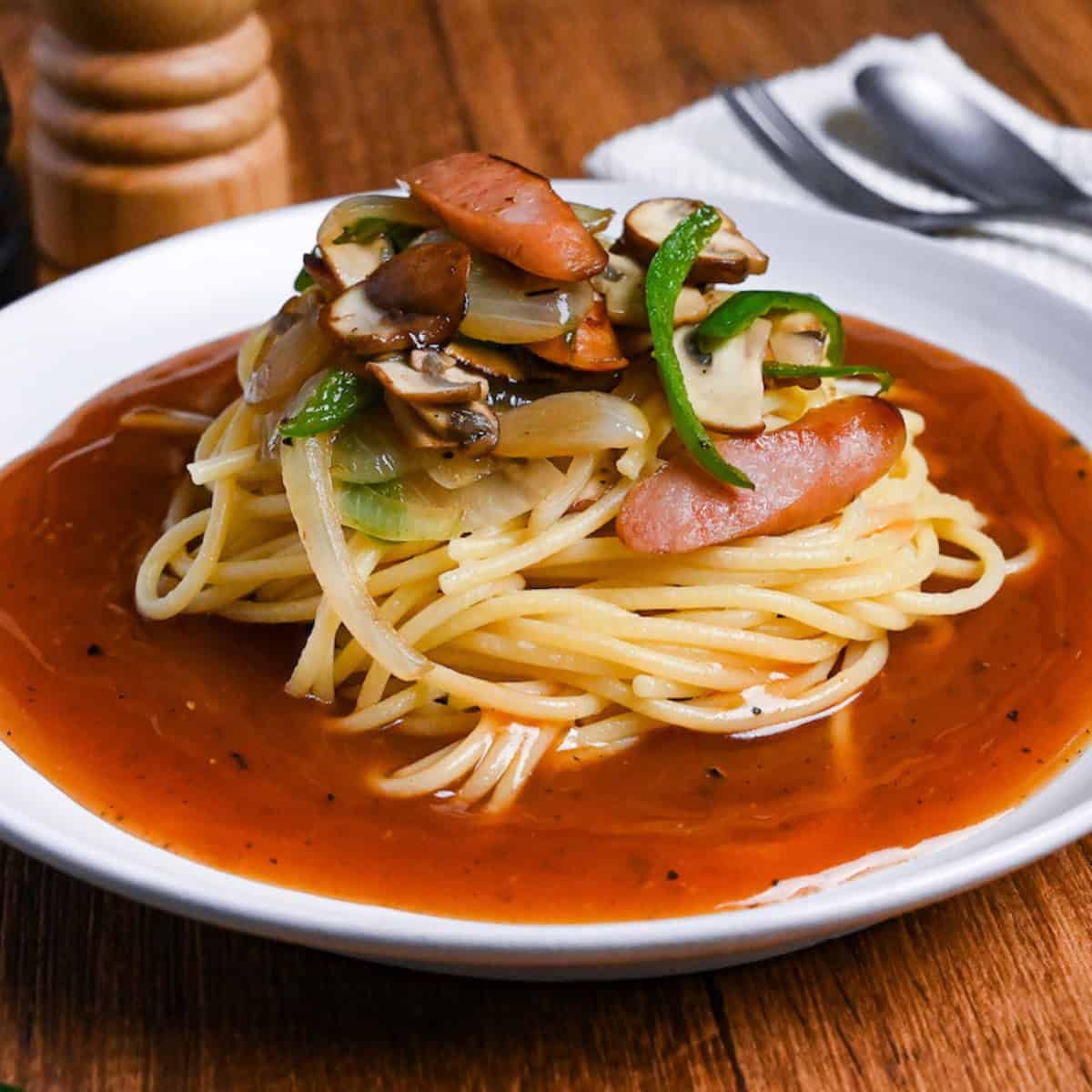 ankake spaghetti on a white plate with salt and pepper shakers in the background