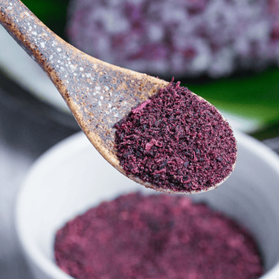 Homemade yukari red/purple shiso rice seasoning powder heaped on a brown ceramic spoon