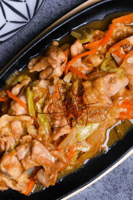 Chicken Keichan Yaki topped with chili threads served in a skillet on wooden base top down view