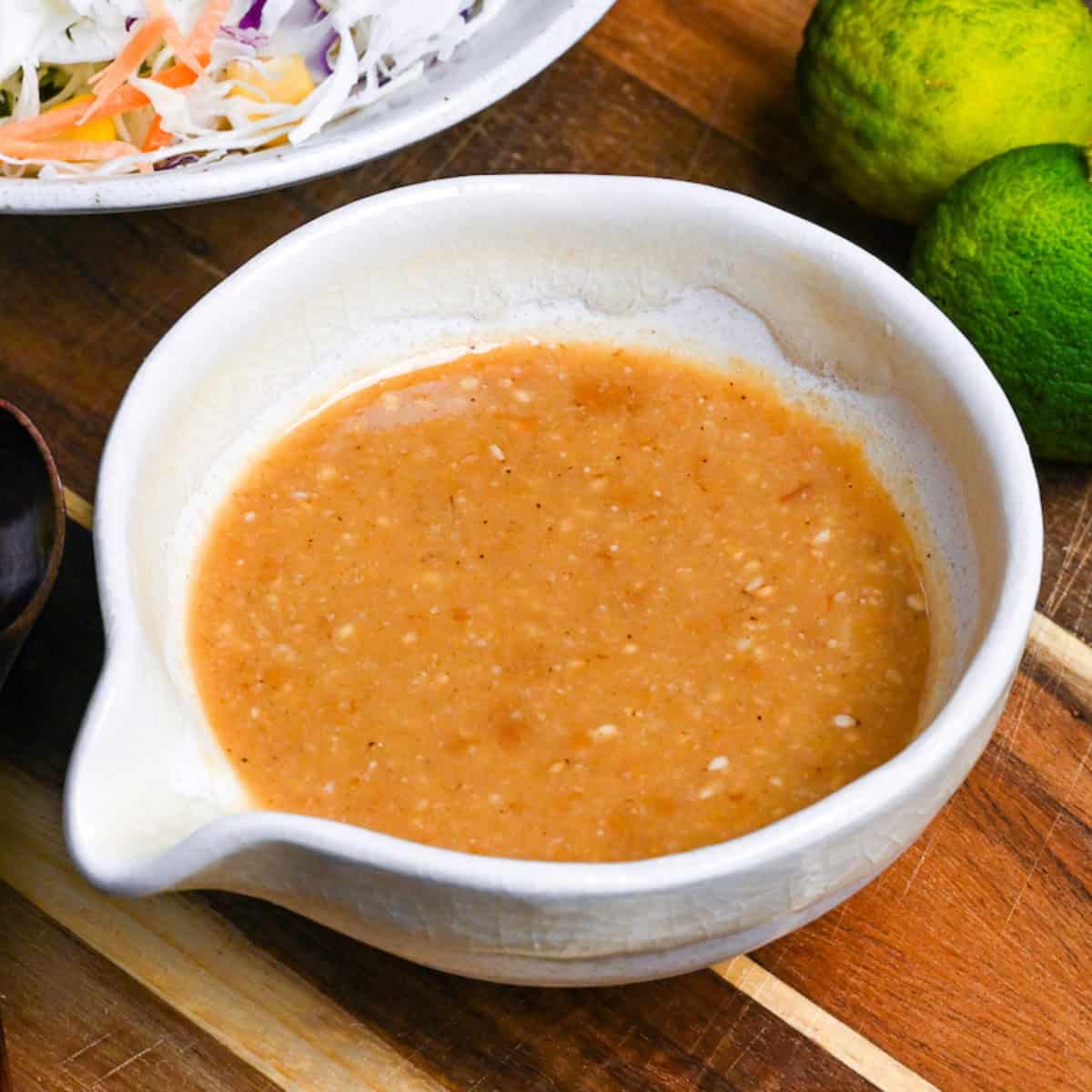 Homemade miso dressing in a Japanese style ceramic jug on a wooden chopping board