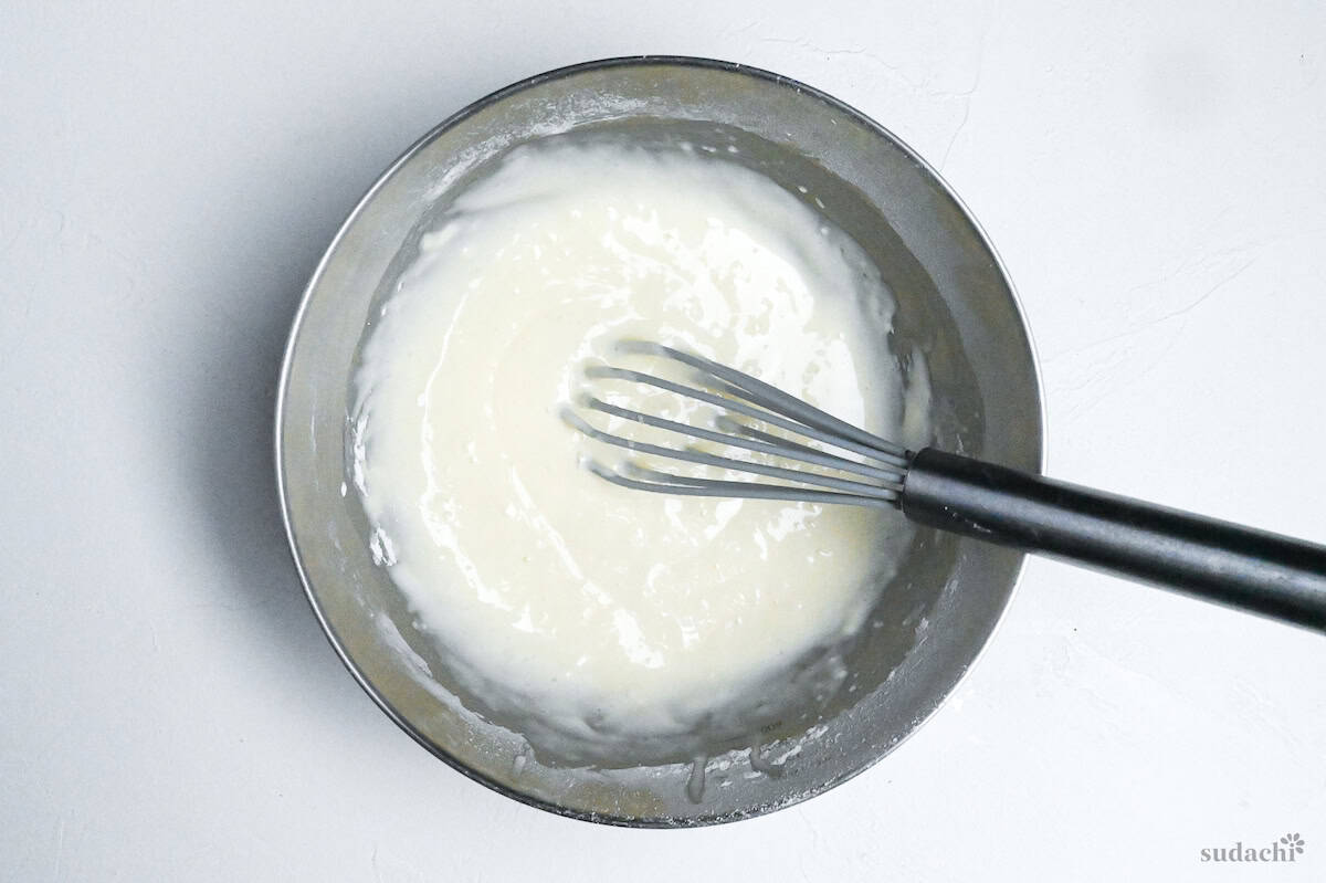 mushi pan batter mixed with a whisk in a steel mixing bowl on a white background