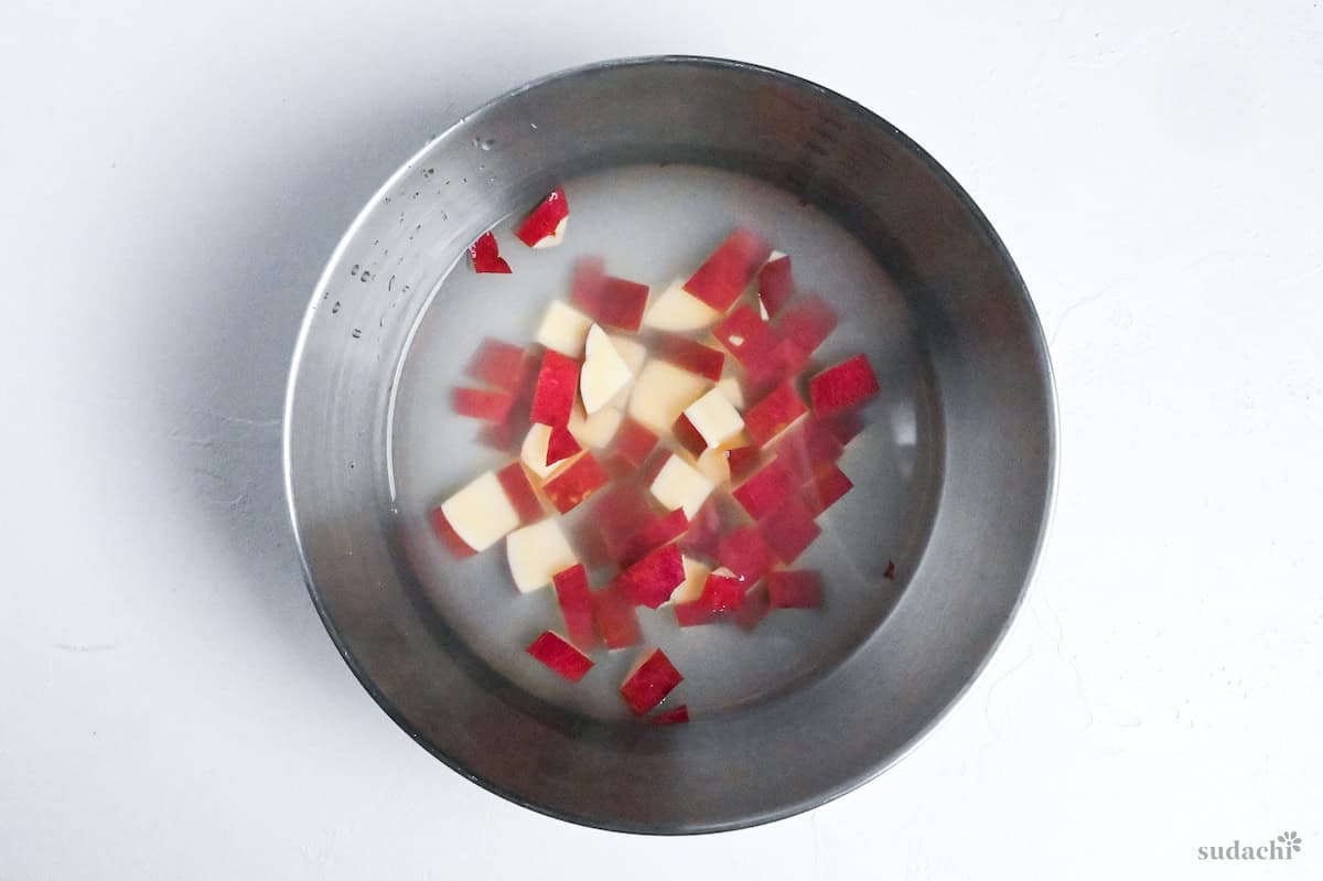 cubed sweet potato soaking in a bowl of water to remove excess starch