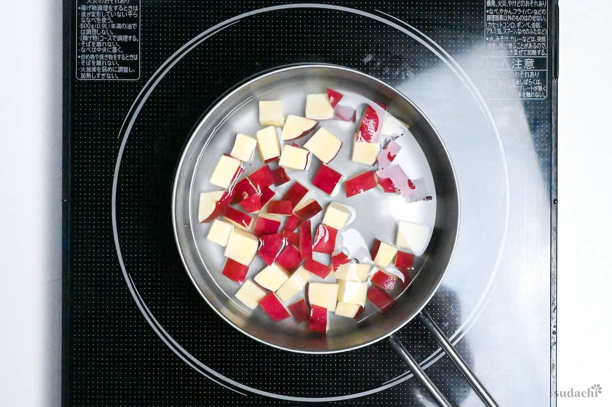 cubed sweet potato simmering with water and sugar in a saucepan on the stove