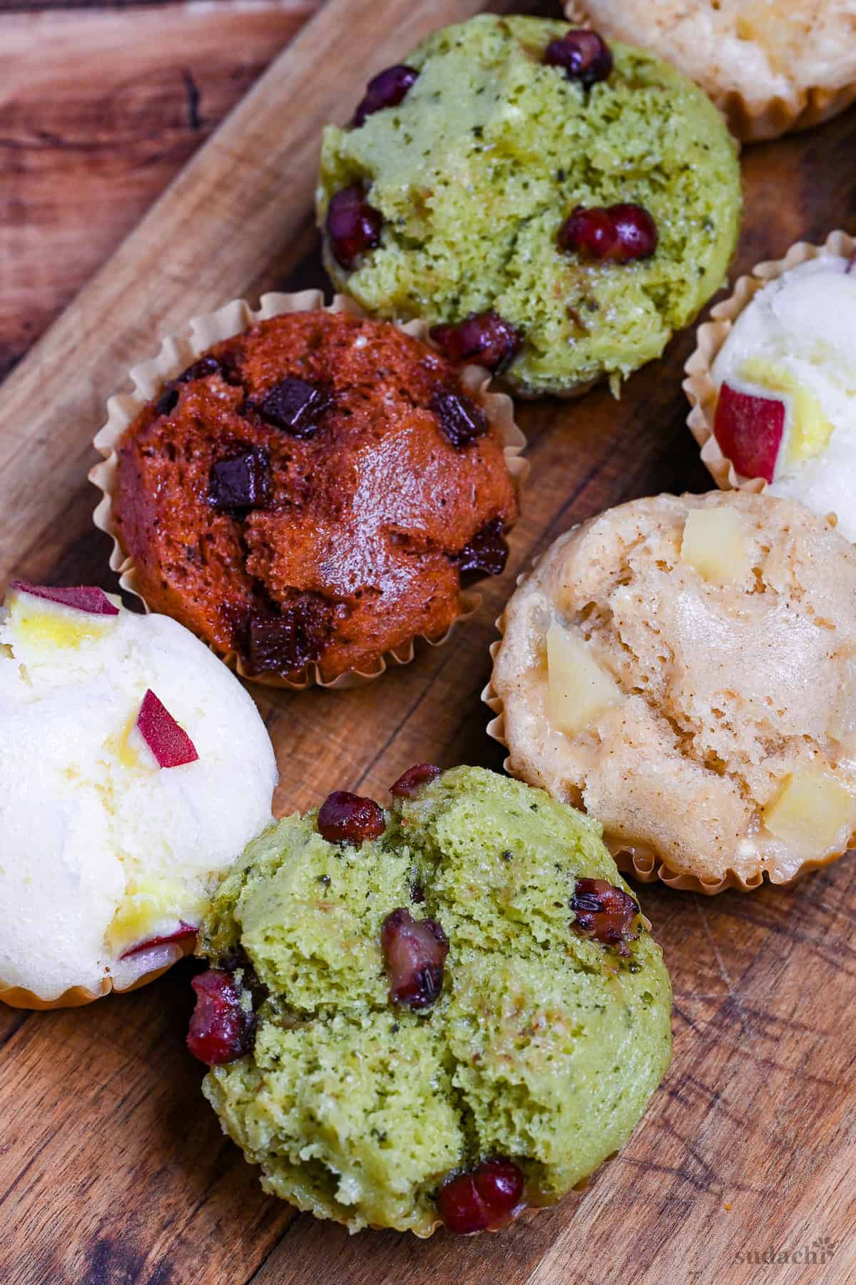 4 different flavors of mushi pan (Japanese steamed cakes) on a wooden chopping board (sweet potato, matcha, chocolate, and tea and apple)