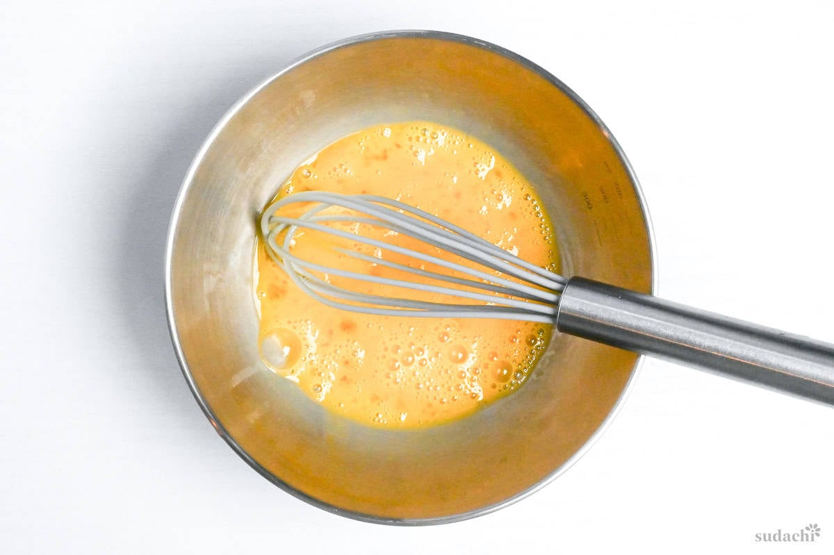 eggs whisked with oil in a mixing bowl