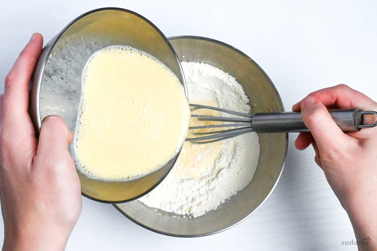 pouring wet ingredients into dry ingredients to make crepe batter