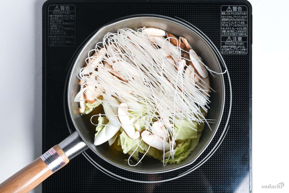 Vegetables and glass noodles in a pot of dashi on the stove