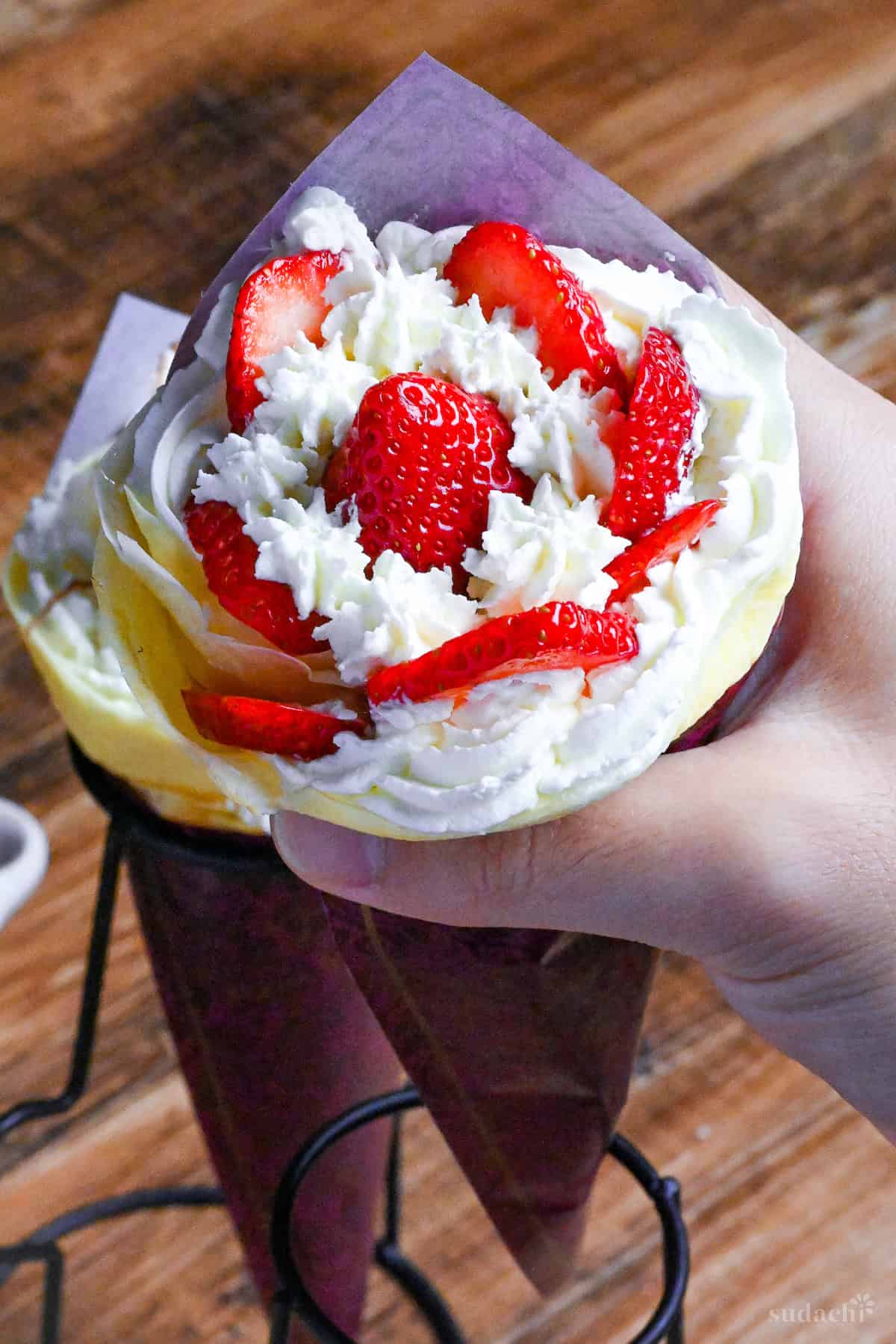 Holding a strawberries and cream Japanese-style Harajuku crepe in hand