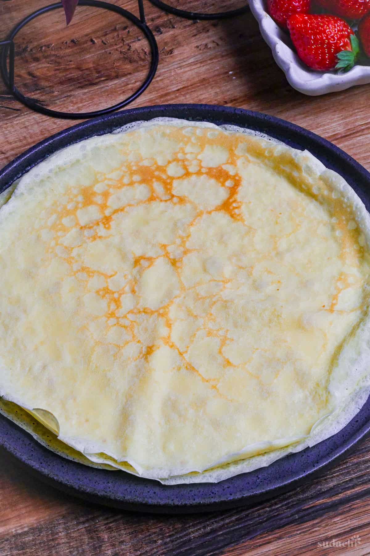 Japanese style crepes flat on a large round black plate (before rolling)