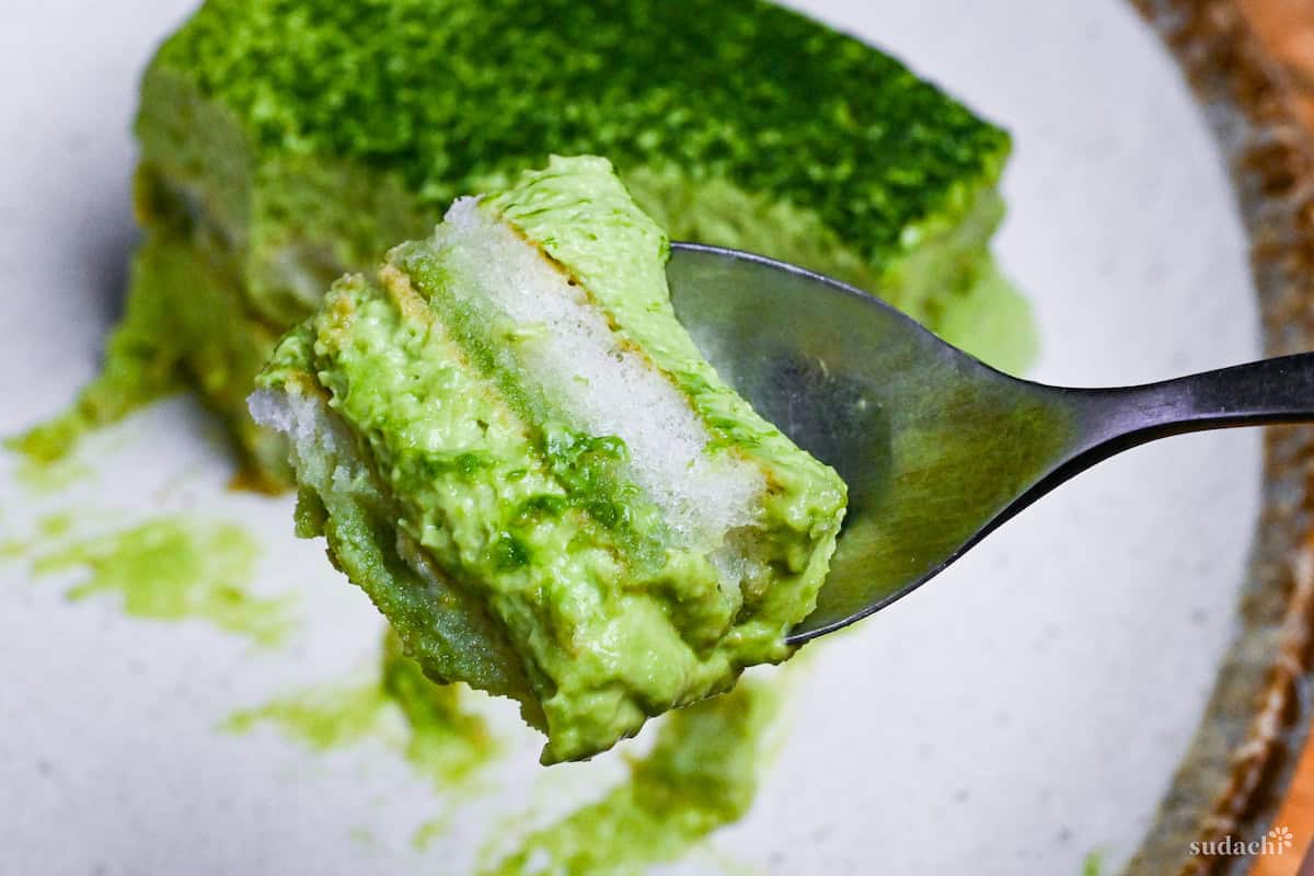 matcha tiramisu on a spoon showing layers of biscuits and cream