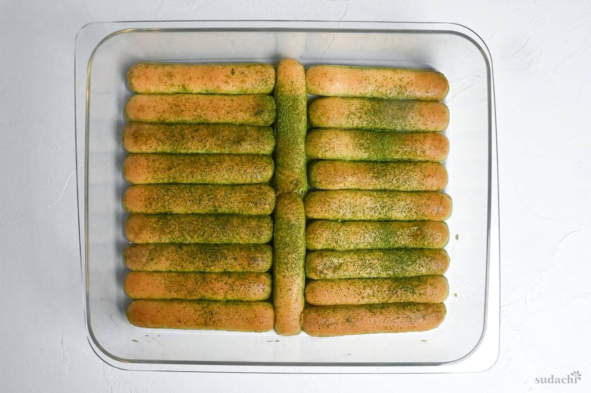 lady fingers dipped in matcha and sprinkled with matcha powder arranged in a rectangular container