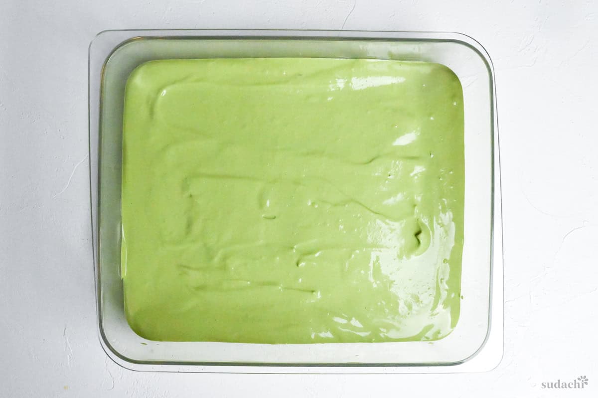 matcha mascarpone cream spread over lady fingers in a rectangular container