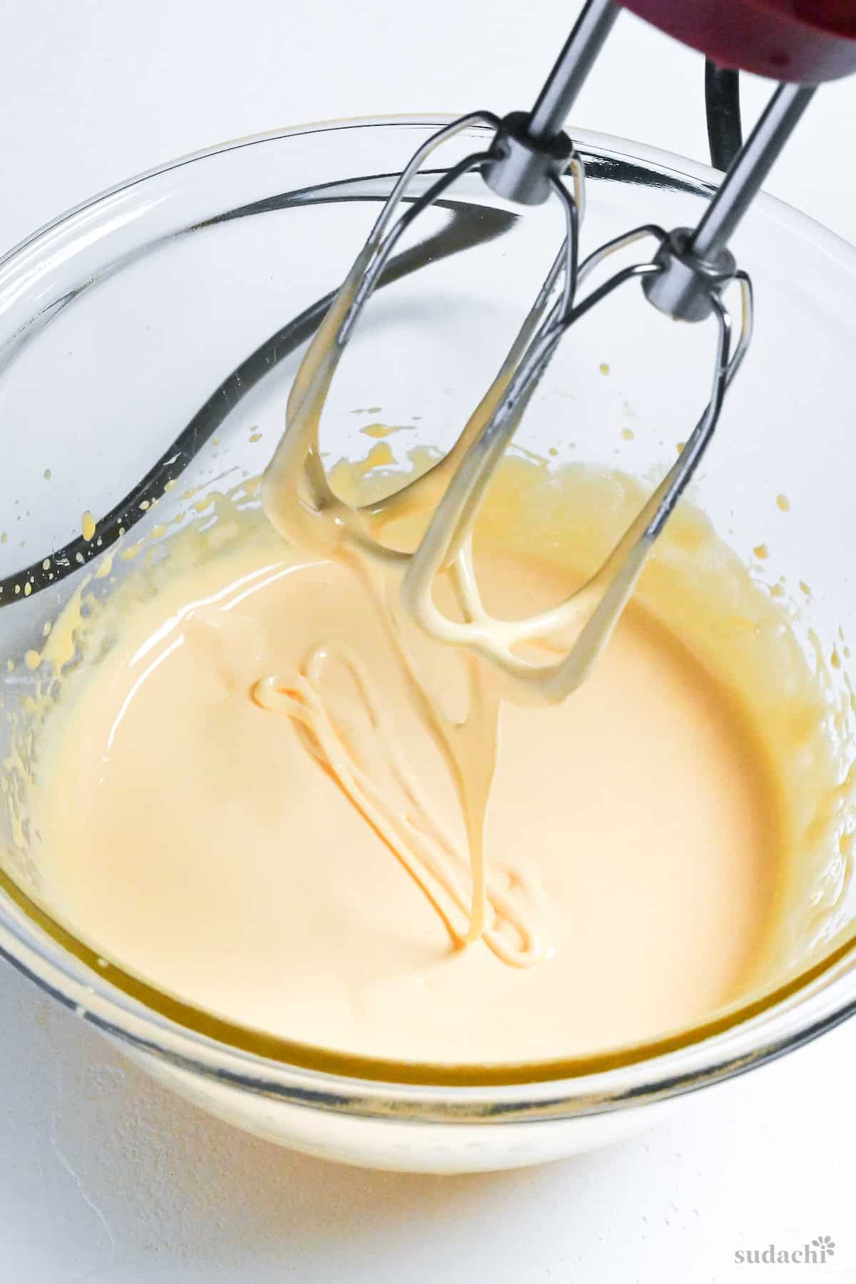 whipped egg yolks and sugar syrup in a glass mixing bowl