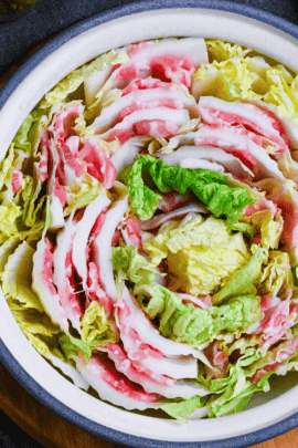 Japanese Mille Feuille Nabe (Pork and Napa Cabbage Hot Pot) in a gray pot on a dark gray background surrounded by various condiments, seasonings and serving bowls