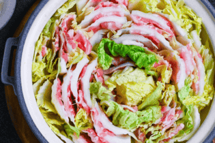 Japanese Mille Feuille Nabe (Pork and Napa Cabbage Hot Pot) in a gray pot on a dark gray background surrounded by various condiments, seasonings and serving bowls