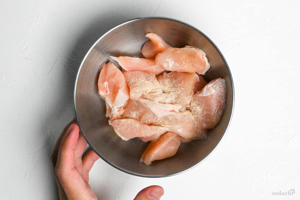 seasoned chicken breast pieces in a steel mixing bowl