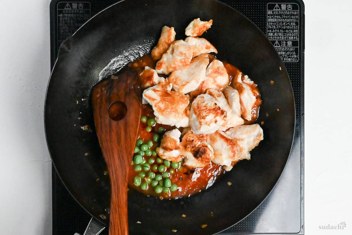 Pan fried chicken breast and green peas in a wok with tori chili sauce