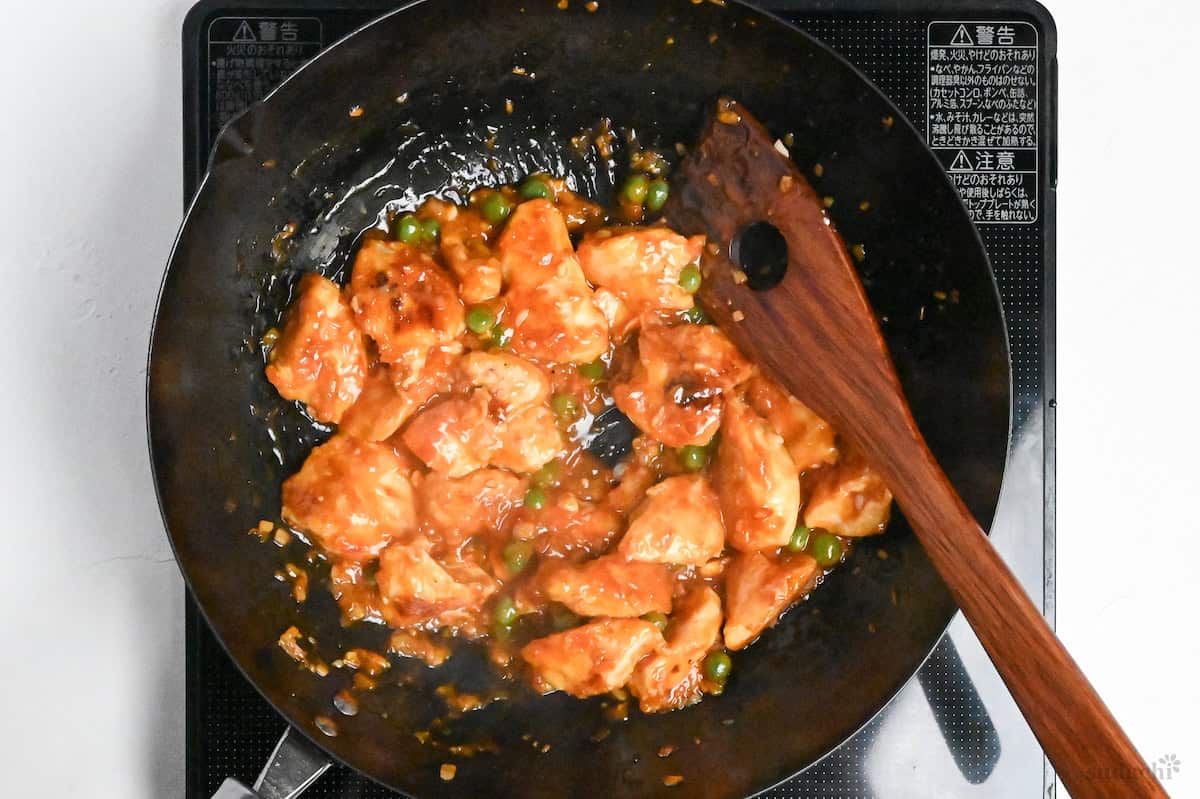 Tori chili in a wok on the stove with wooden spatula