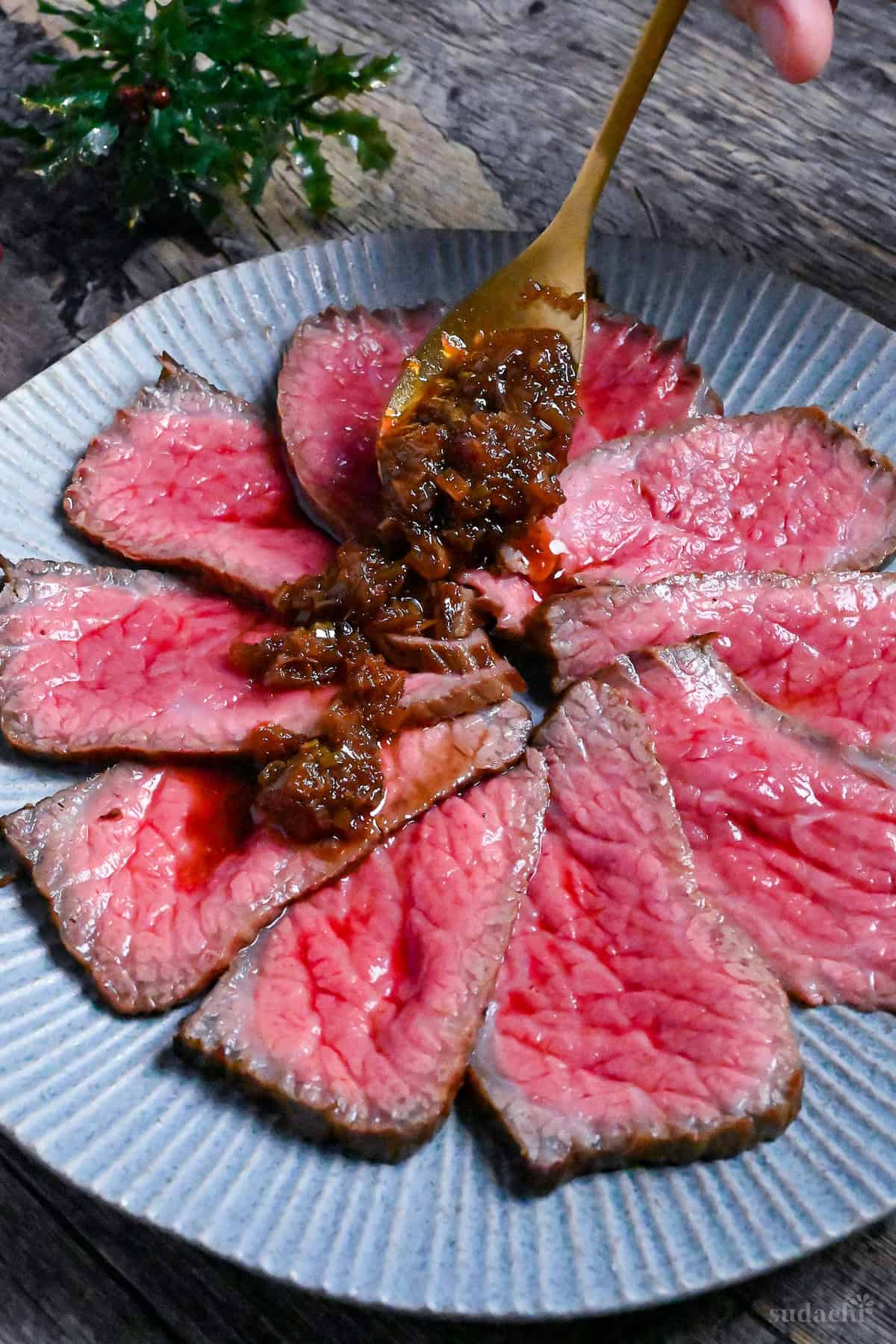 spooning wafu sauce over thinly sliced Japanese-style roast beef