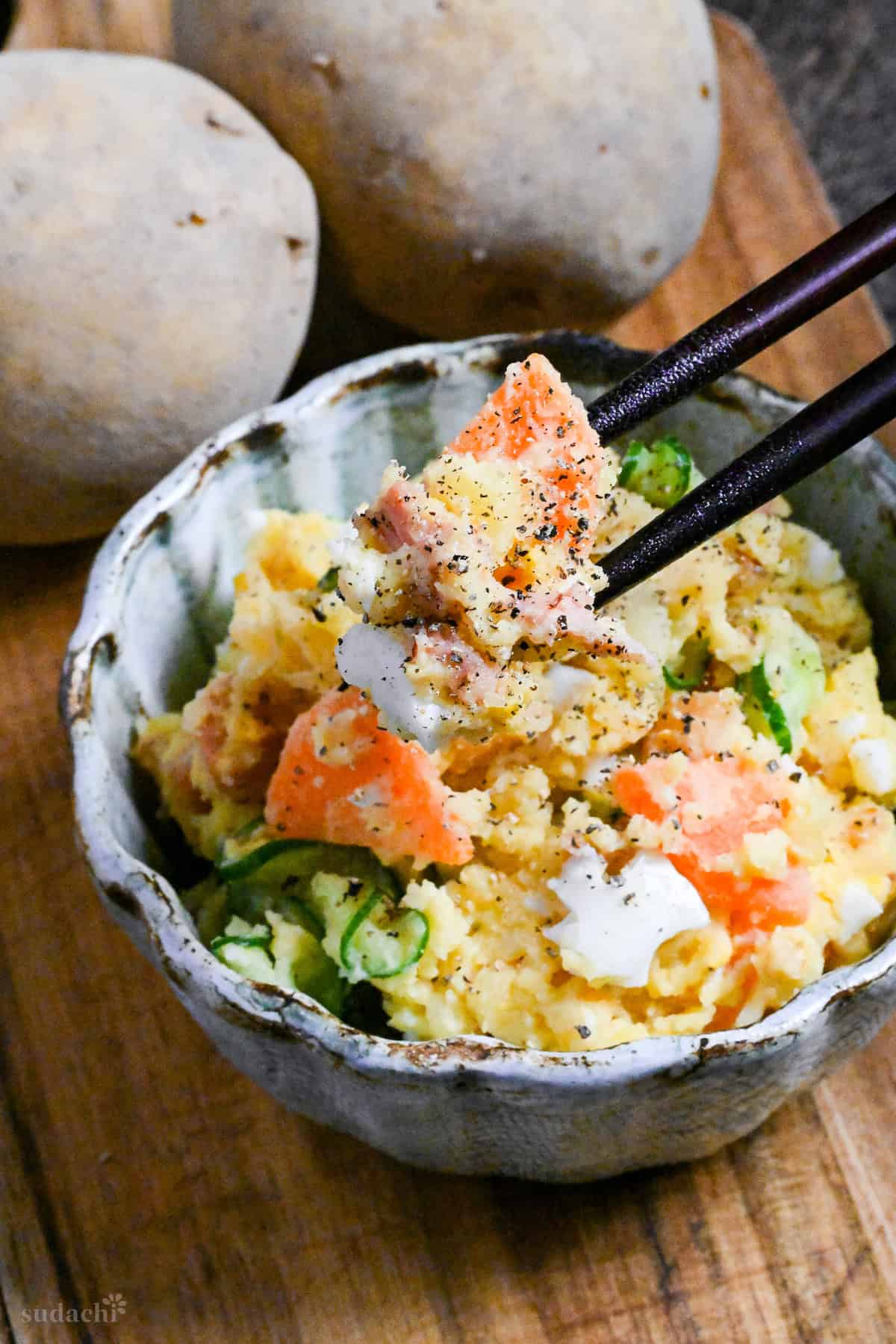 Japanese izakaya style potato salad in a light blue bowl on a wooden board