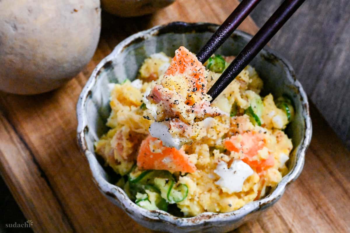 Japanese izakaya style potato salad in a light blue bowl on a wooden board