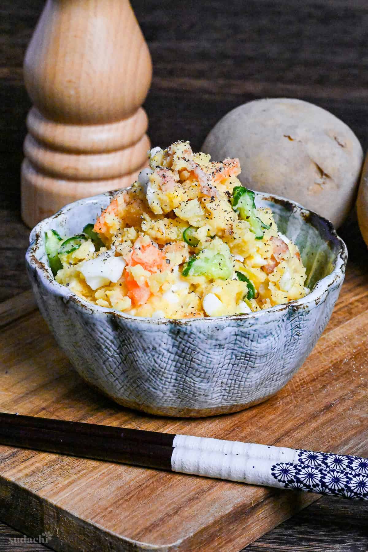 Japanese izakaya style potato salad in a light blue bowl on a wooden board