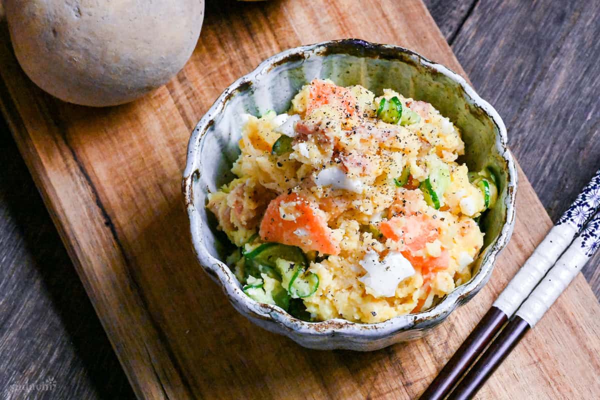 Japanese izakaya style potato salad in a light blue bowl on a wooden board