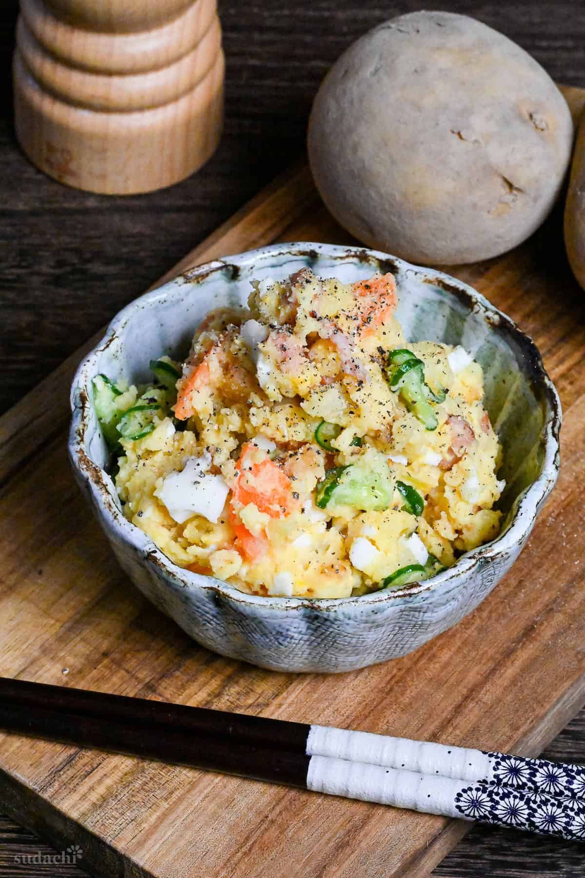Japanese izakaya style potato salad in a light blue bowl on a wooden board
