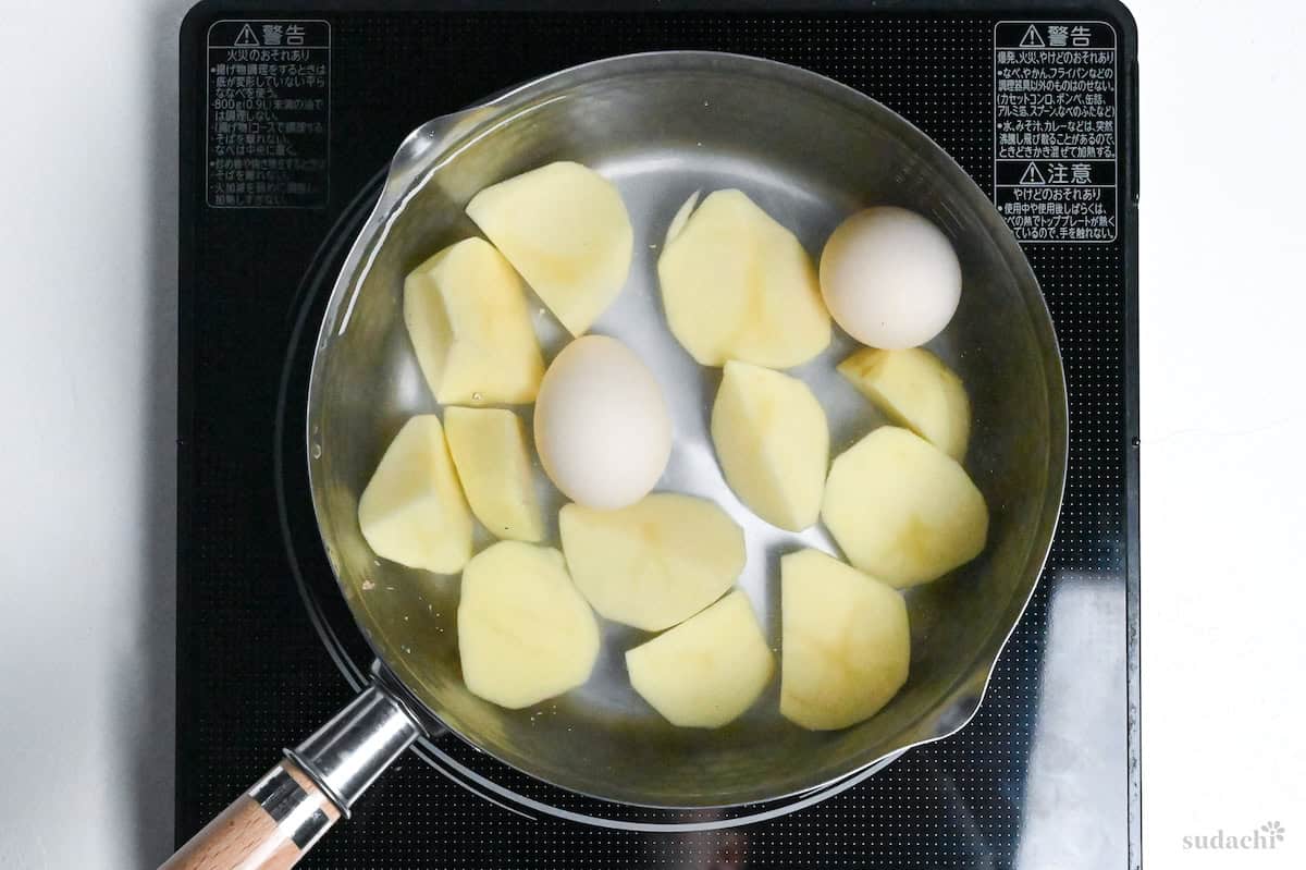 potatoes and two eggs in a pot of water on the stove