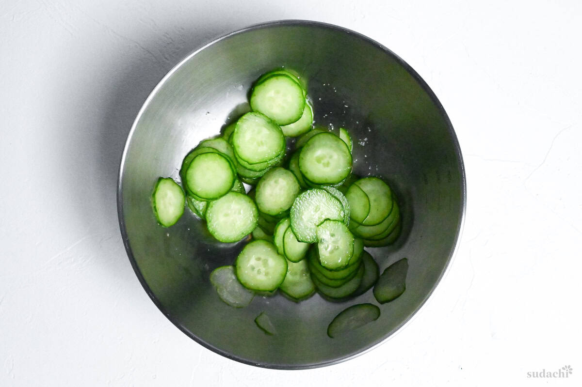 salted cucumber slices in a mixing bowl