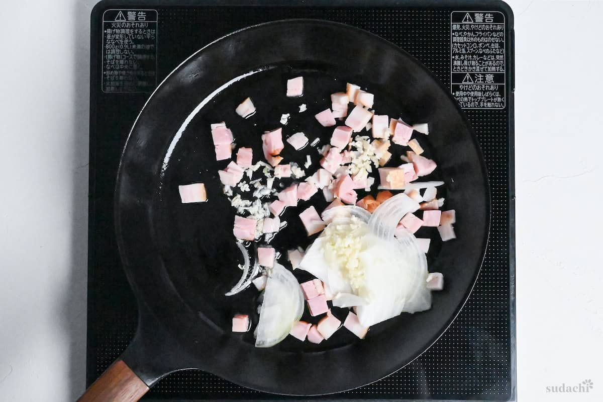 bacon and onions frying in a pan on the stove