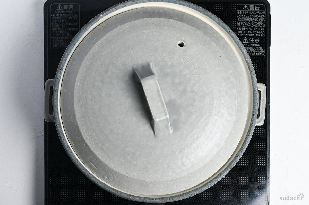 A gray ceramic pot with lid on the stove (cooking curry hot pots step)