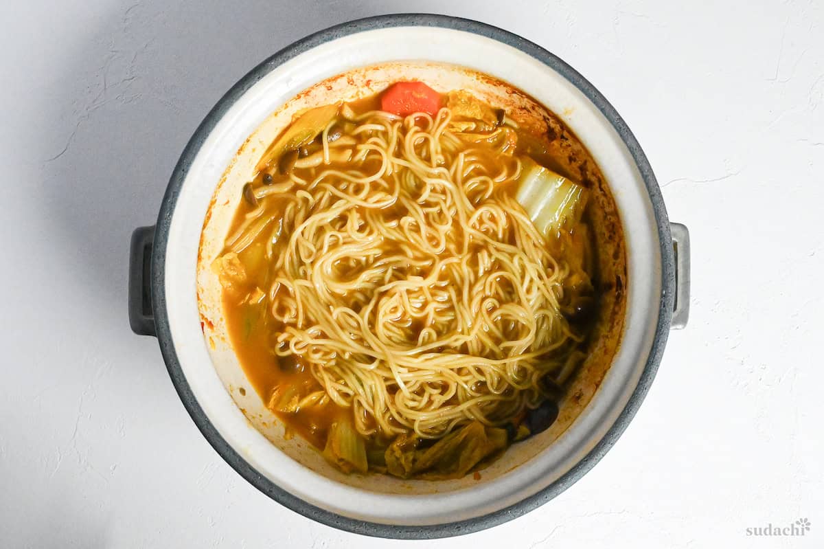 pre-boiled ramen noodles in leftover curry hot pot broth on a white background