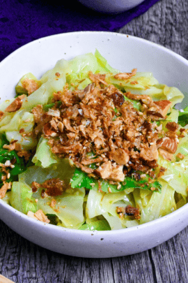 mugen cabbage in a white bowl on ashy wood surface with furikake in a bowl on a blue cloth in the background