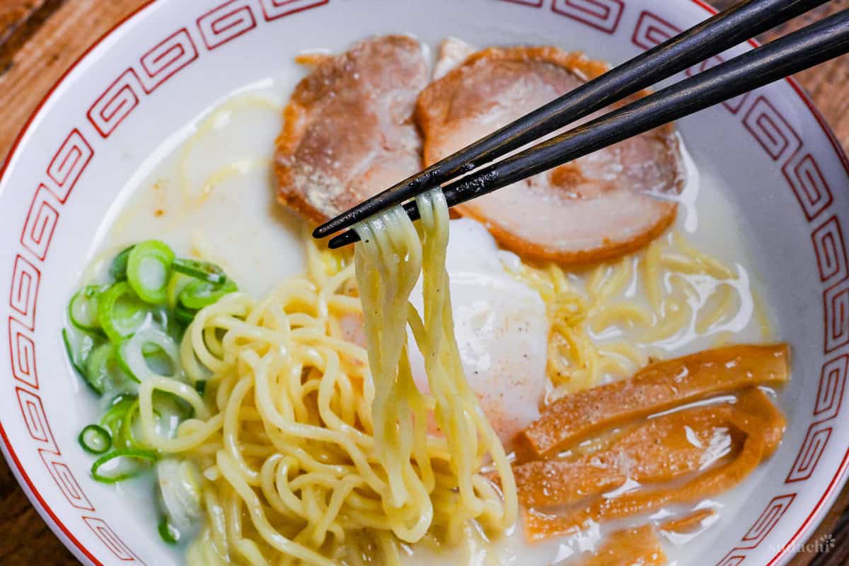 Sugakiya Ramen Copycat recipe served in a white and red ramen bowl with black chopsticks holding up noodles