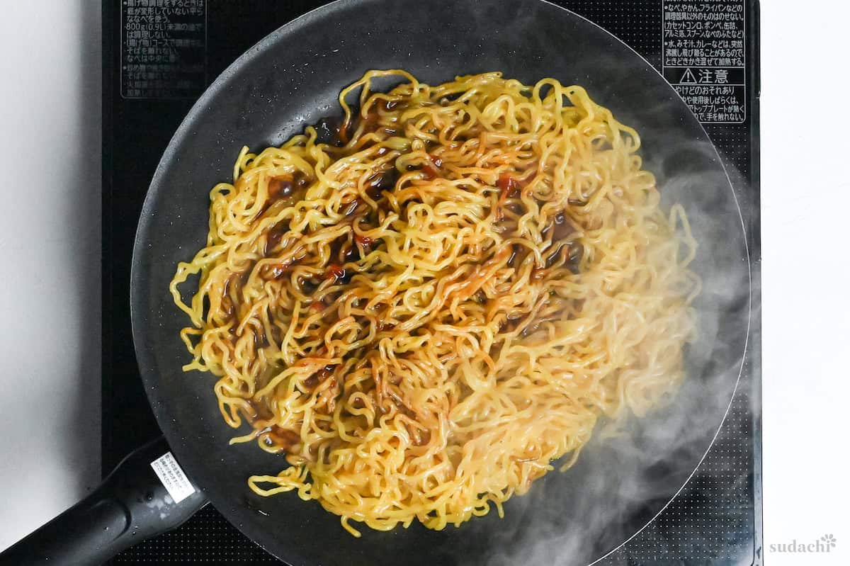 fried ramen noodles with yakisoba sauce in a frying pan on the stove