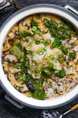 Daikon radish hot pot in a gray pot on a black wood-effect background top down