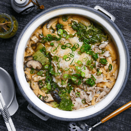 Daikon radish hot pot in a gray pot on a black wood-effect background top down