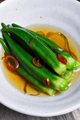 shio okra in a white bowl with chili and shio kombu on an ashy wooden background