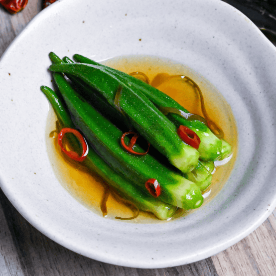 shio okra in a white bowl with chili and shio kombu on an ashy wooden background