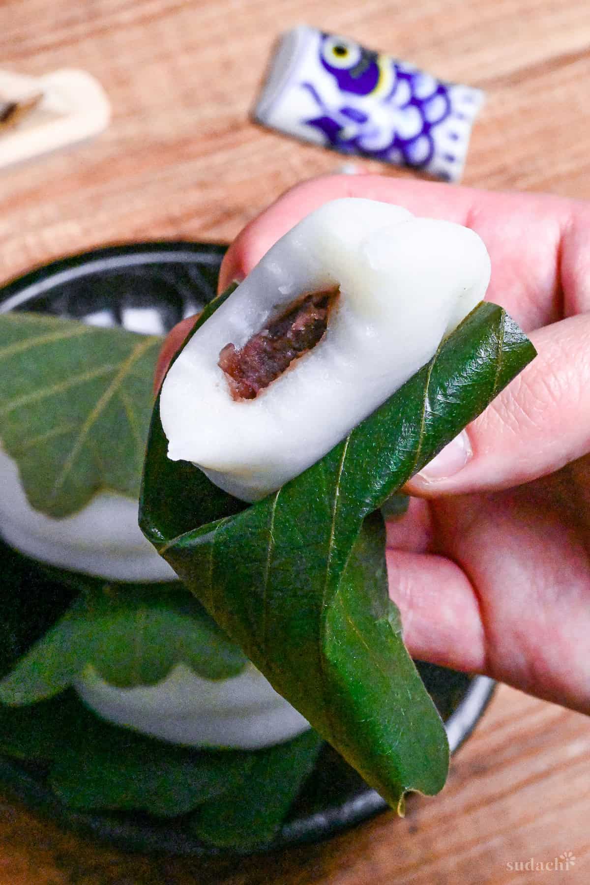 A bite taken out of a kashiwa mochi revealing anko red bean filling