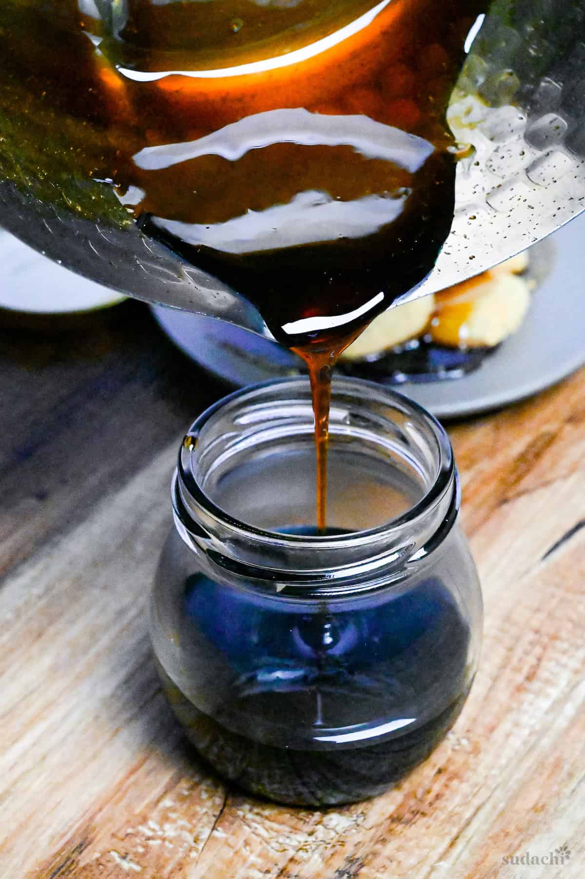 Pouring homemade kuromitsu (Japanese dark sugar syrup) from a pan into a small jar