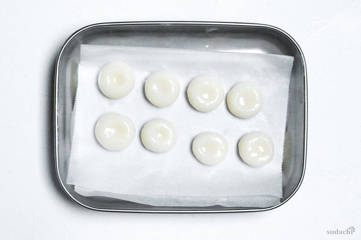 cooked shiratama dango on a piece of baking paper in a steel container ready for freezing